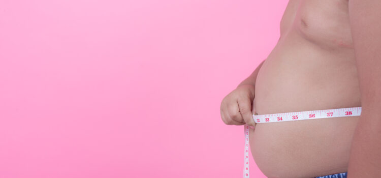 Obese boy who is overweight on a pink background.