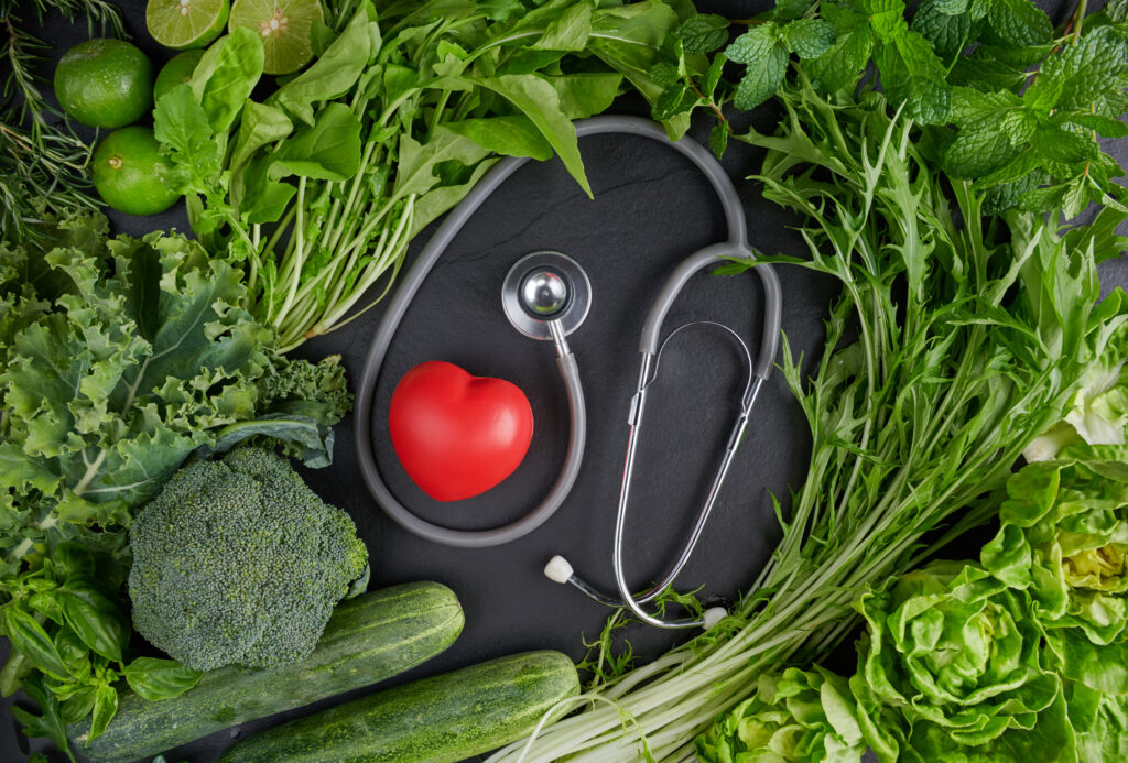 Healthy heart concept. Green organic vegetarian products with heart near stethoscope.