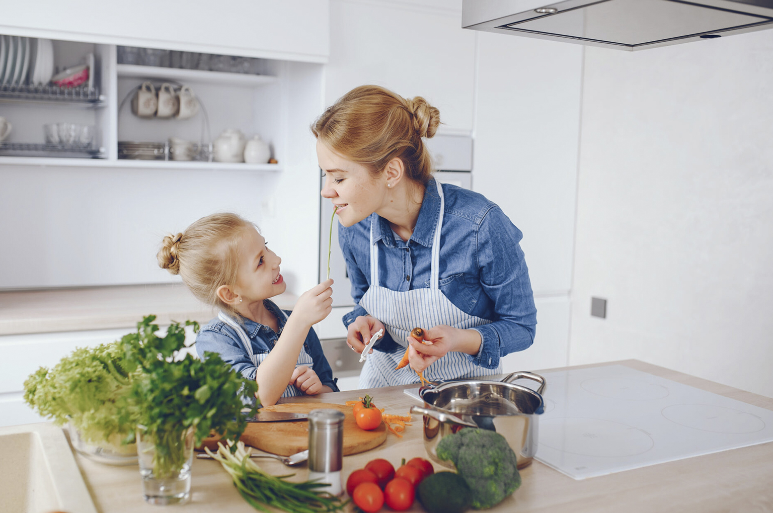 Matka w niebieskiej koszuli przygotowuje sałatkę wraz z córką