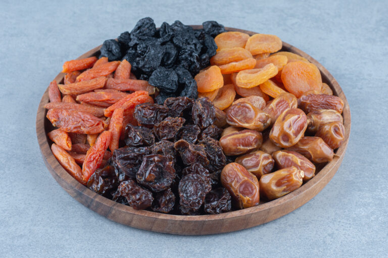 Dried fruits in the wooden board, on the marble background.